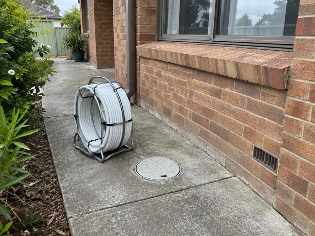 Capped access cover in a concrete side path beside a brick house in Gymea